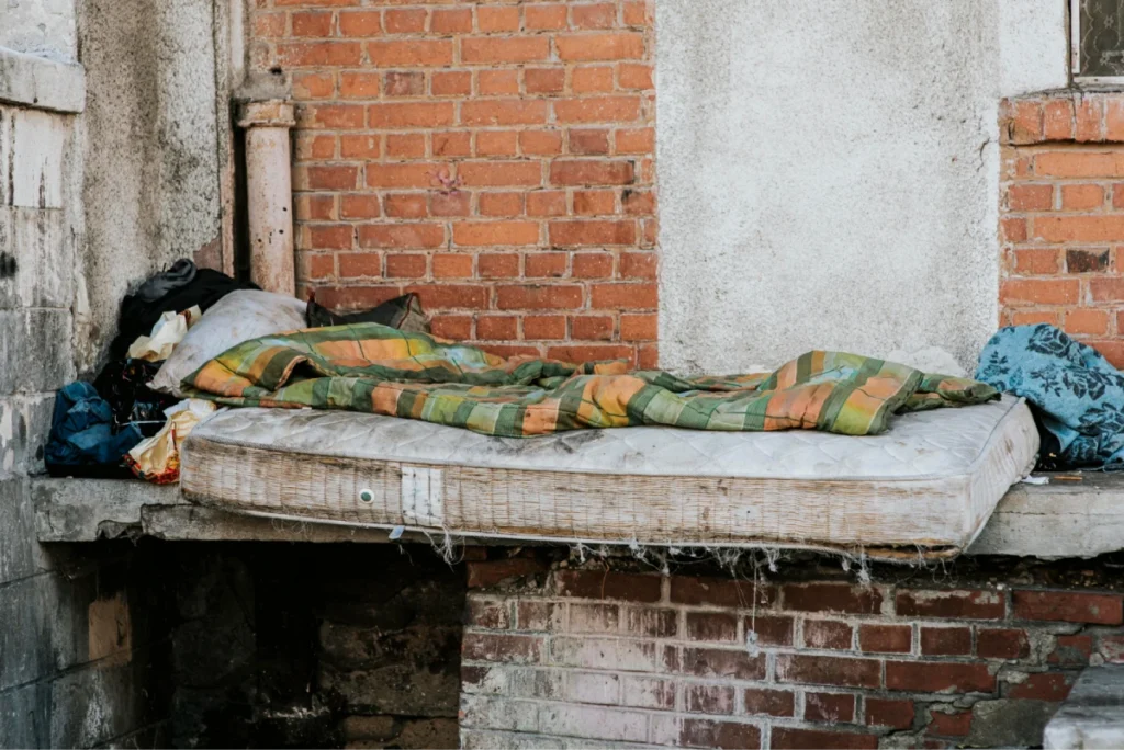 Old mattress with blanket on a dilapidated ledge.