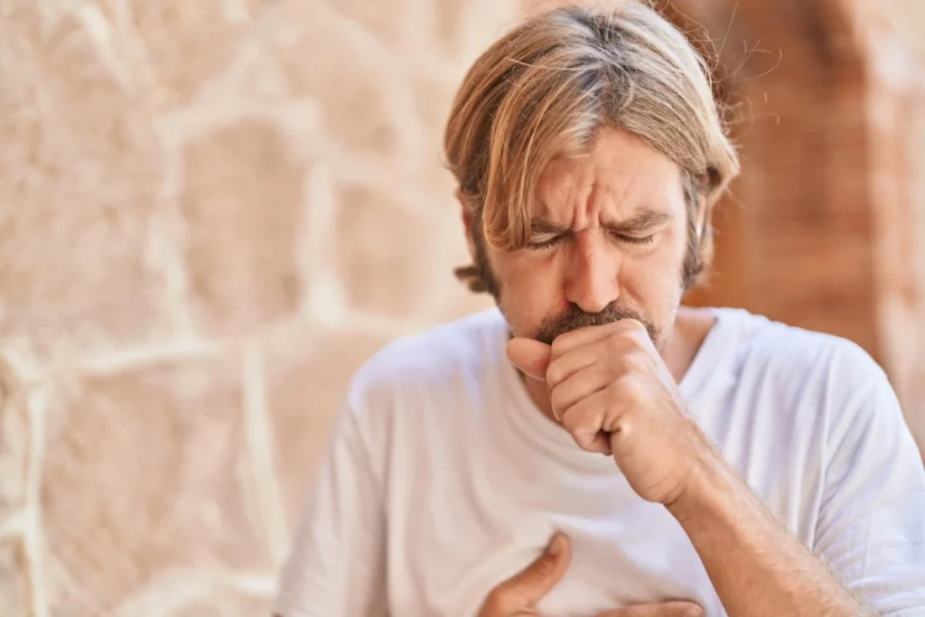 Man coughing while holding his chest.