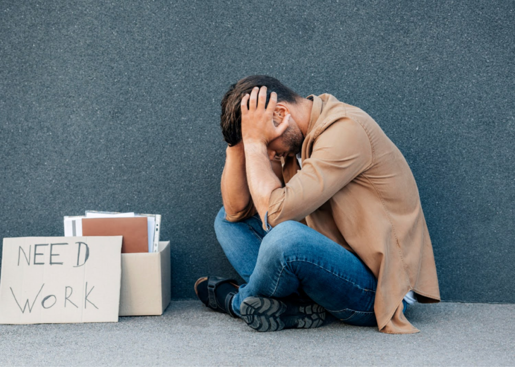 Man sitting with 'Need Work' sign.